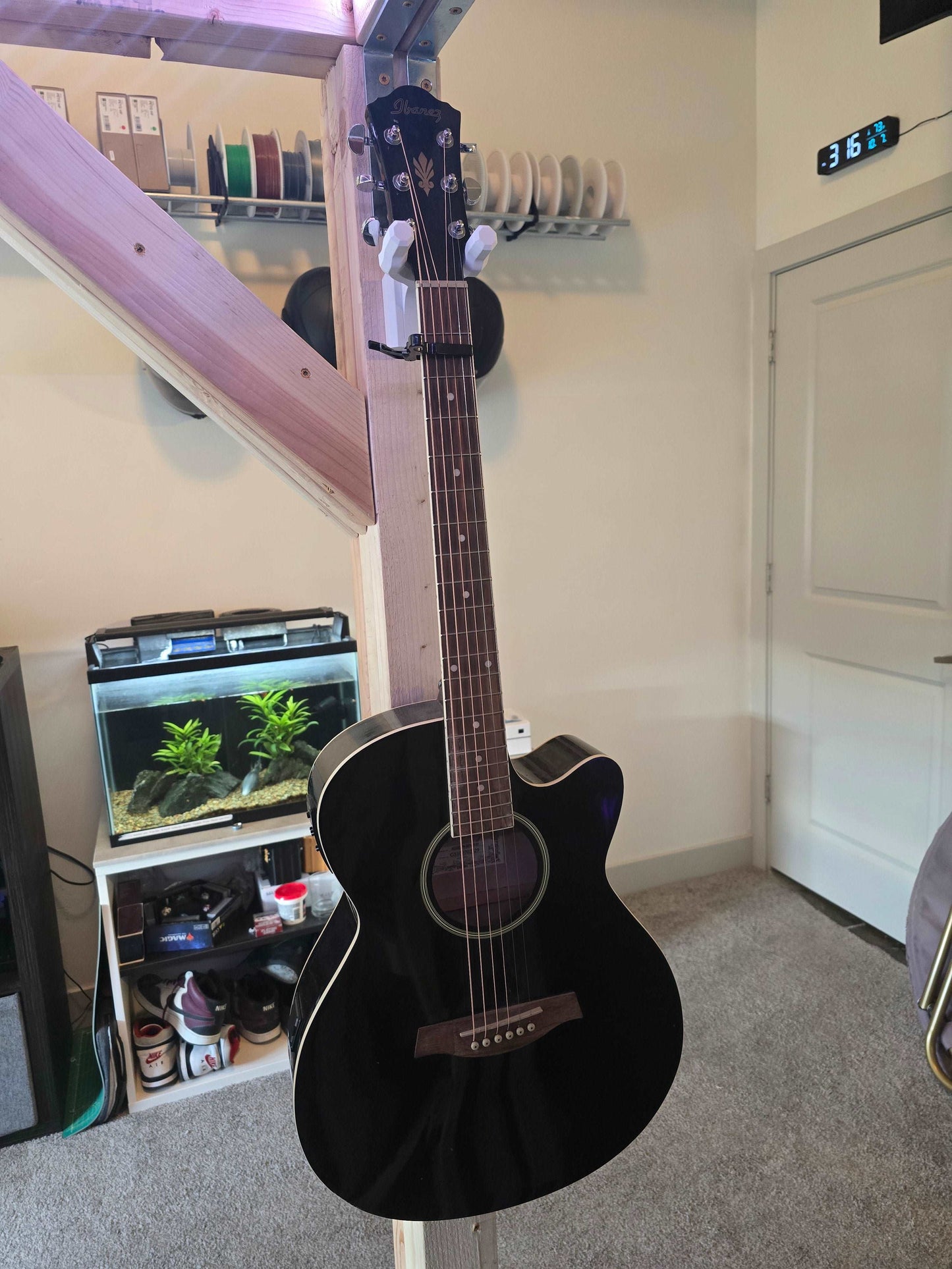 Black acoustic guitar with wall mount bracket in bedroom setting