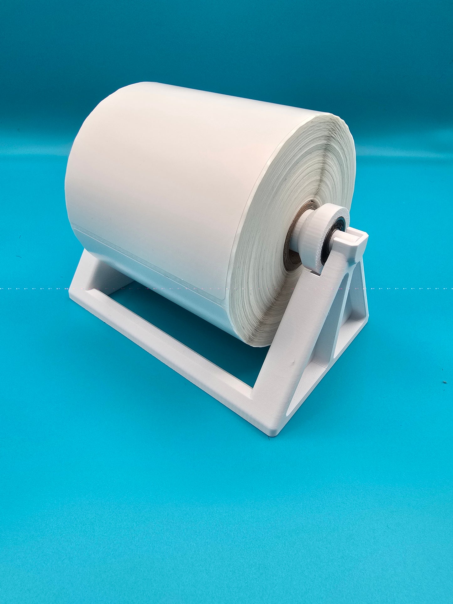 White thermal printer roll spool stand for desktop shipping label printers, designed by Tarbon Designs.