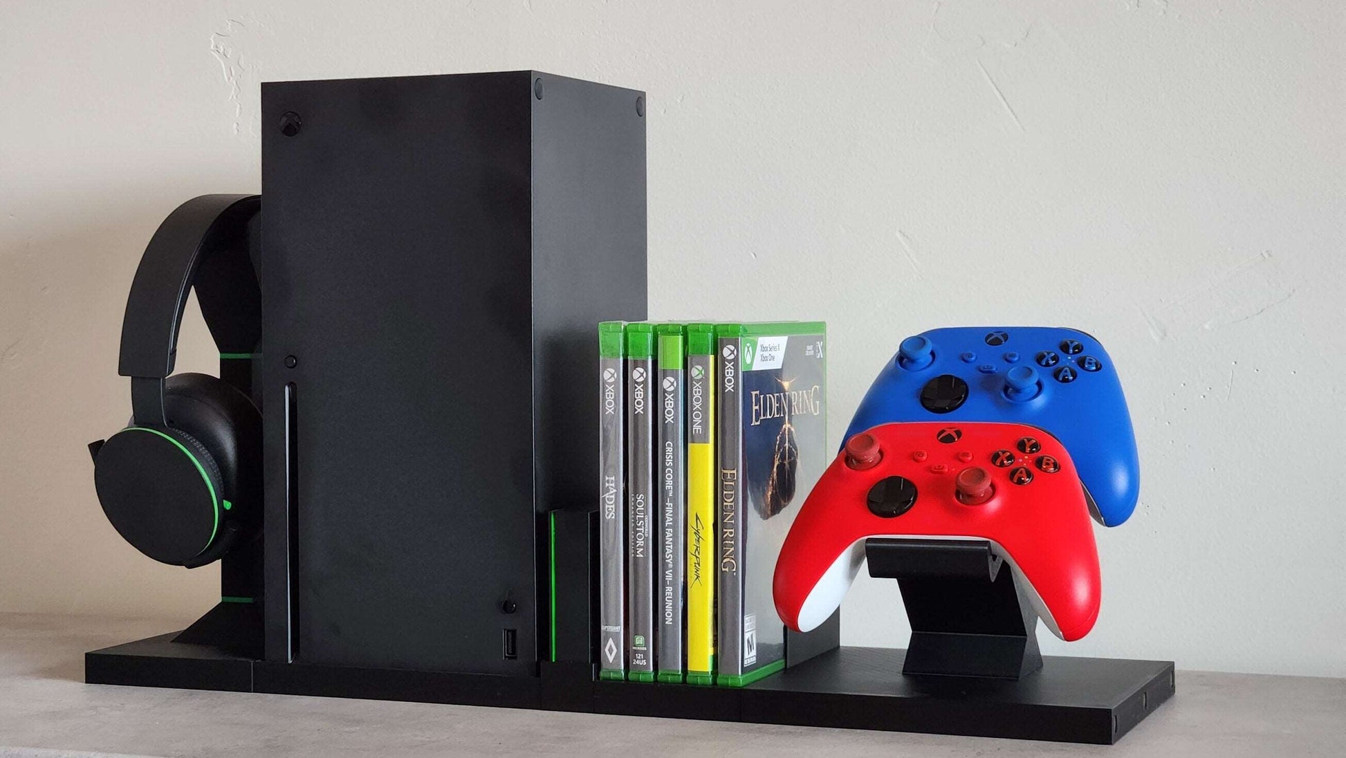 Modular Xbox game console organizer with magnetic stands, headphone holder, and colorful game controllers in a sleek, organized display.