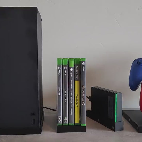 Innovative video game console organizer system with modular magnetic design, showcasing XBox console, controllers, and game cases on a white background.